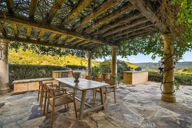 view of patio with a pergola, a mountain view, and an outdoor kitchen