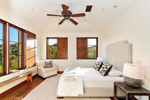 bedroom with vaulted ceiling, light hardwood / wood-style flooring, multiple windows, and ceiling fan