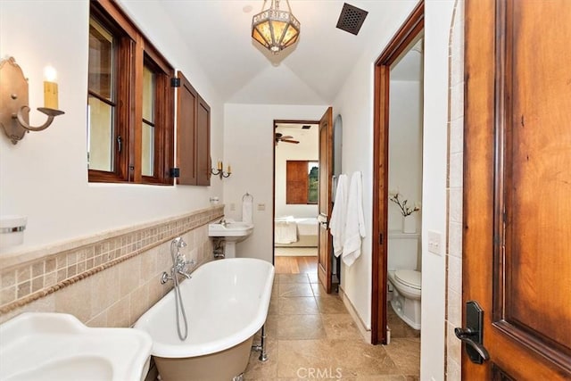 2835 Hermitage Rd, Ojai, CA 93023 - bathroom featuring tile walls, ensuite bathroom, a soaking tub, toilet, and lofted ceiling