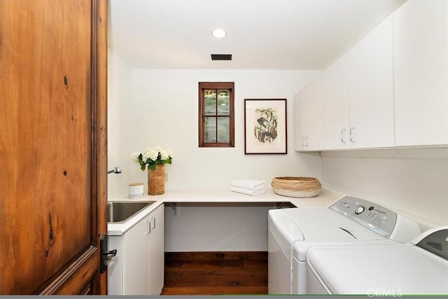 laundry area featuring separate washer and dryer, sink, cabinets, and wood-type flooring