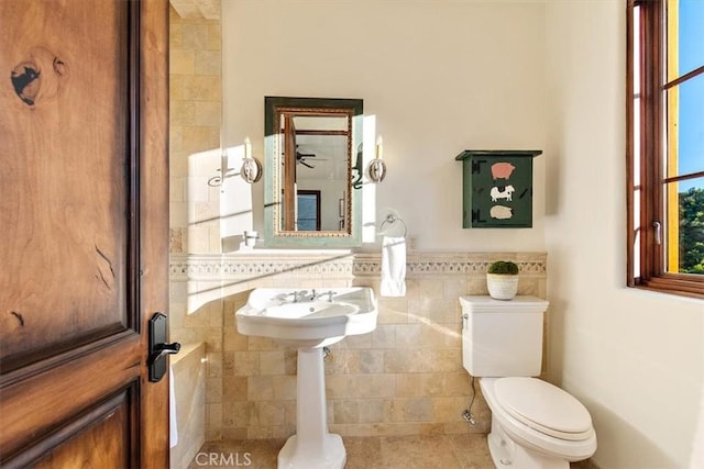 bathroom featuring tile patterned floors, toilet, and tile walls