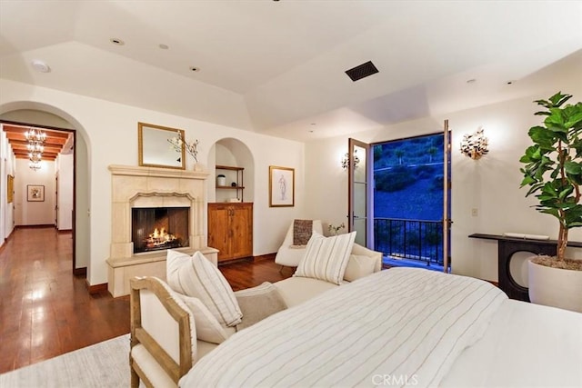 bedroom featuring a raised ceiling, access to exterior, and dark wood-type flooring