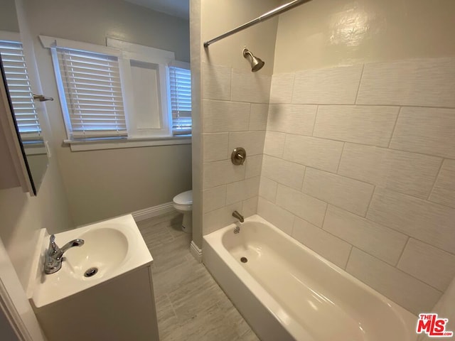 full bathroom with tiled shower / bath, vanity, and toilet