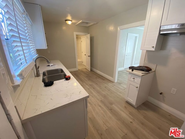 kitchen with light wood-type flooring, white cabinetry, and sink