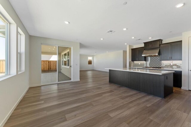 kitchen with dark wood-type flooring, dark brown cabinetry, sink, and a kitchen island with sink