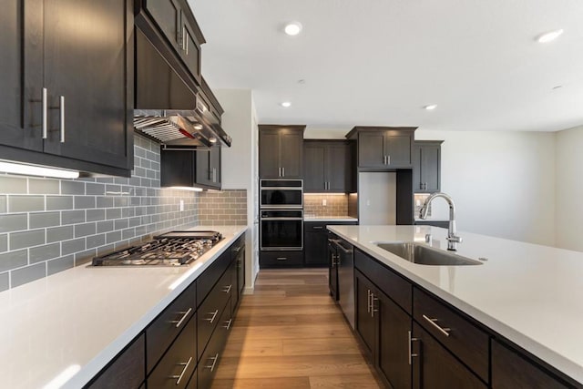 kitchen with tasteful backsplash, light hardwood / wood-style floors, sink, stainless steel appliances, and dark brown cabinets