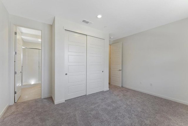 unfurnished bedroom with light carpet and a closet