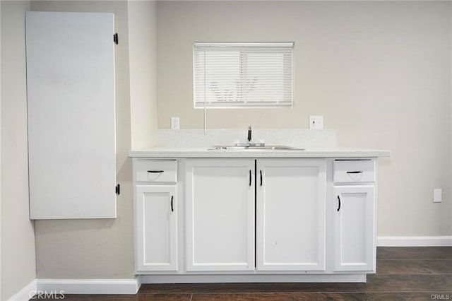 bar featuring dark hardwood / wood-style floors, white cabinetry, and sink