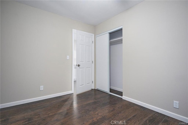 unfurnished bedroom with dark wood-type flooring and a closet