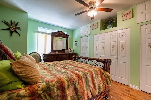 bedroom featuring light wood-type flooring, ceiling fan, and multiple closets