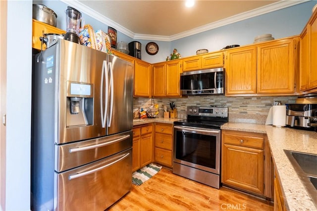 kitchen with sink, crown molding, decorative backsplash, light wood-type flooring, and appliances with stainless steel finishes