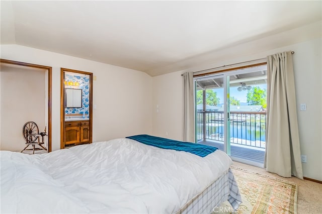 carpeted bedroom with vaulted ceiling, ensuite bath, and access to exterior