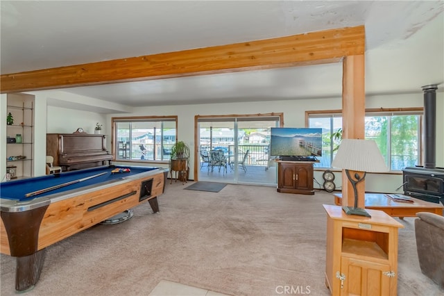 recreation room featuring a wood stove, beamed ceiling, light colored carpet, and billiards