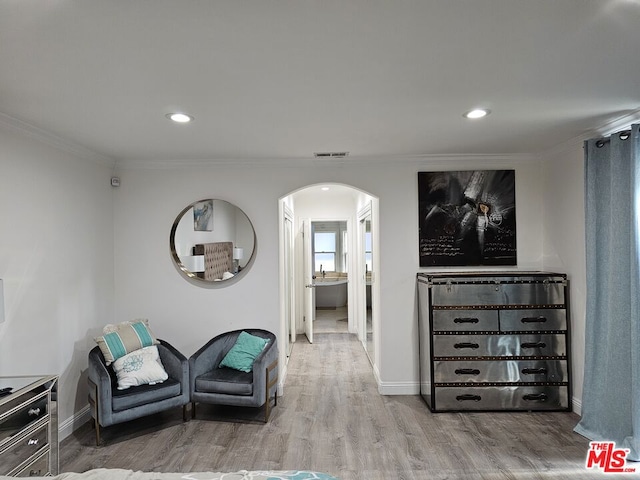 living area featuring crown molding and light hardwood / wood-style flooring