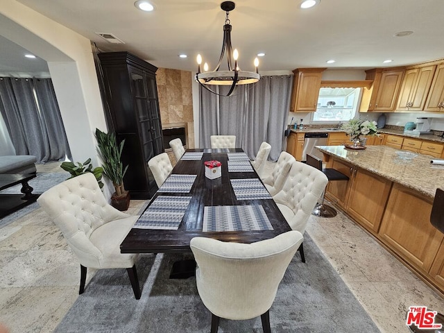 dining room featuring a tiled fireplace and an inviting chandelier