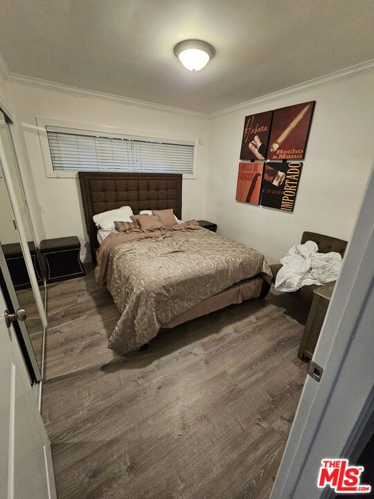 bedroom with hardwood / wood-style flooring and crown molding