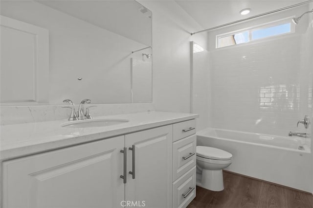 bathroom featuring washtub / shower combination, toilet, vanity, and wood finished floors