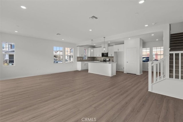 unfurnished living room featuring plenty of natural light, recessed lighting, and visible vents