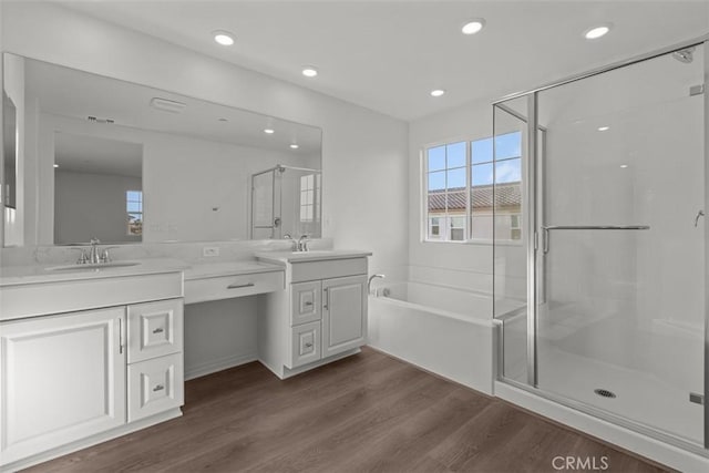 bathroom featuring a shower stall, vanity, a bath, and wood finished floors