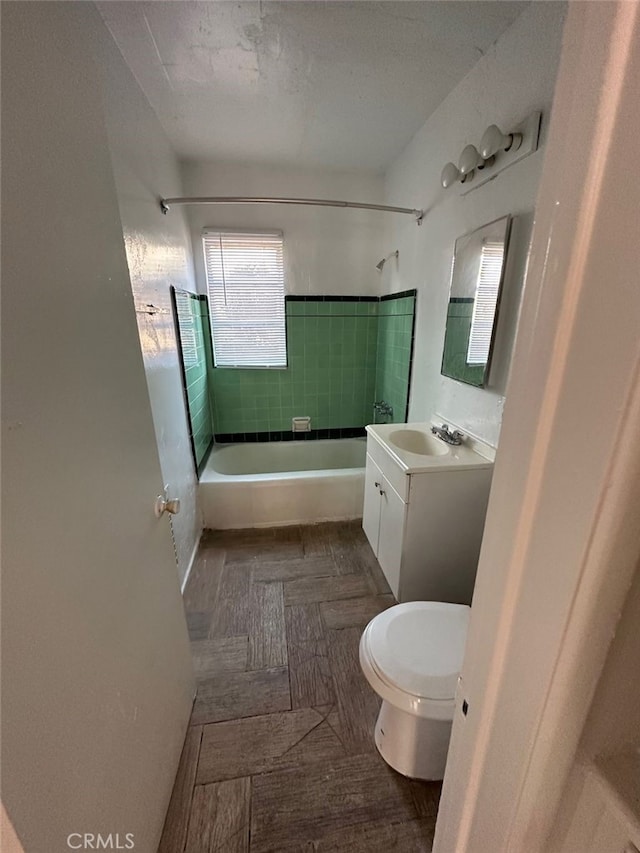 full bathroom featuring vanity, tiled shower / bath combo, and toilet