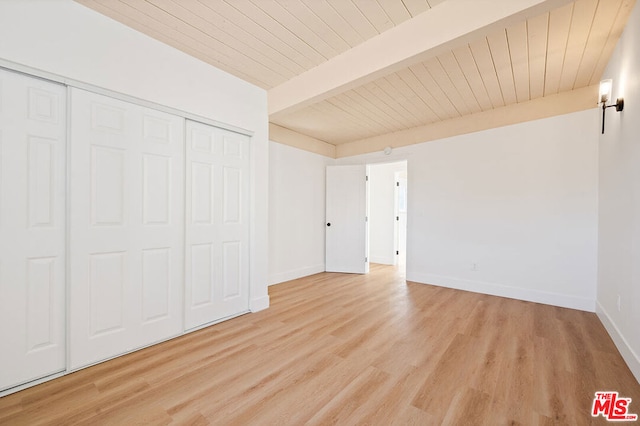 unfurnished bedroom with a closet, beam ceiling, and light wood-type flooring