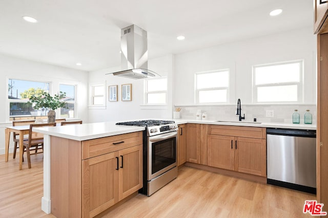 kitchen featuring sink, island exhaust hood, light wood-type flooring, and appliances with stainless steel finishes