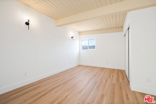 spare room with beamed ceiling and light hardwood / wood-style flooring