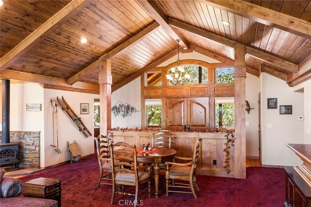 dining area with dark carpet, beamed ceiling, a wood stove, and wooden ceiling