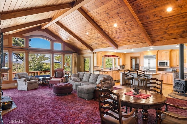 living room featuring light colored carpet, high vaulted ceiling, wooden ceiling, beamed ceiling, and a wood stove