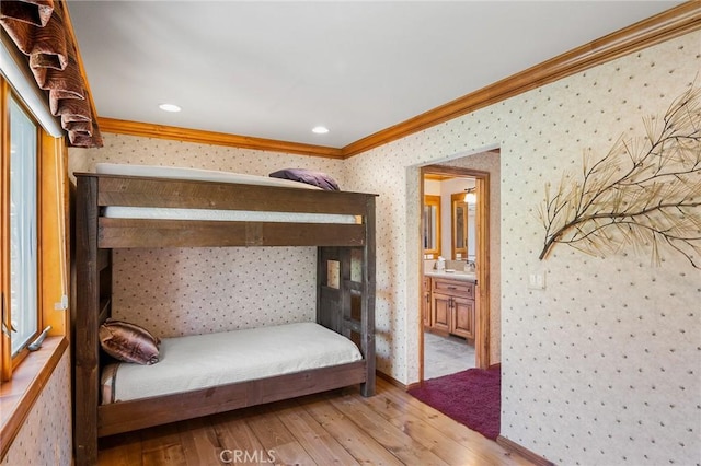 bedroom featuring ensuite bath, ornamental molding, and light wood-type flooring