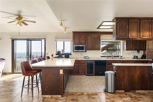 kitchen featuring a breakfast bar, a healthy amount of sunlight, and black dishwasher