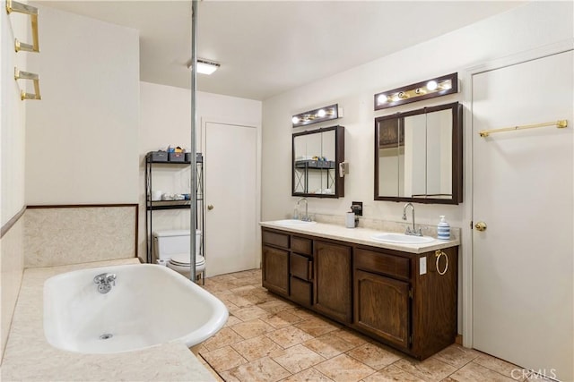bathroom with vanity, a bath, and toilet