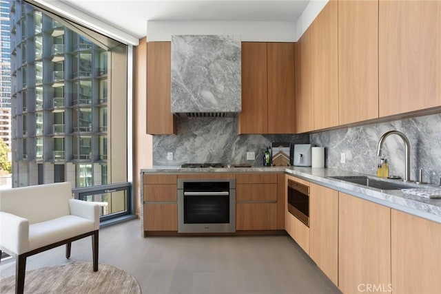 kitchen featuring light stone countertops, sink, tasteful backsplash, light hardwood / wood-style flooring, and appliances with stainless steel finishes