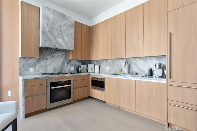 kitchen with light hardwood / wood-style floors, sink, backsplash, and appliances with stainless steel finishes