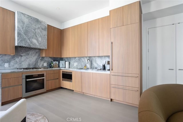 kitchen with tasteful backsplash, sink, stainless steel appliances, and light hardwood / wood-style floors