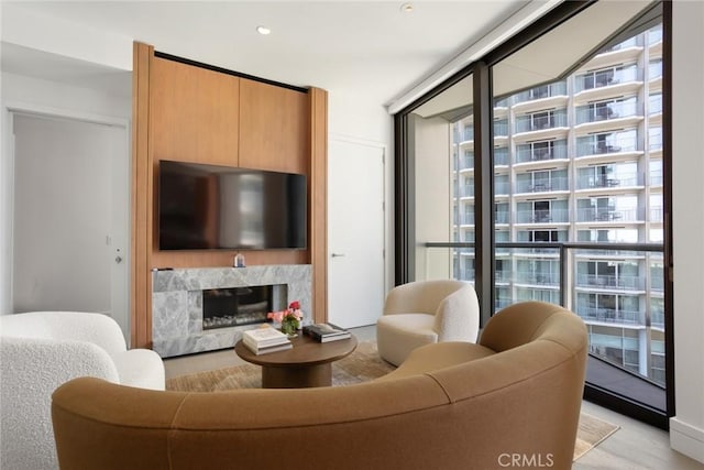 living room with a high end fireplace, light hardwood / wood-style flooring, expansive windows, and a healthy amount of sunlight