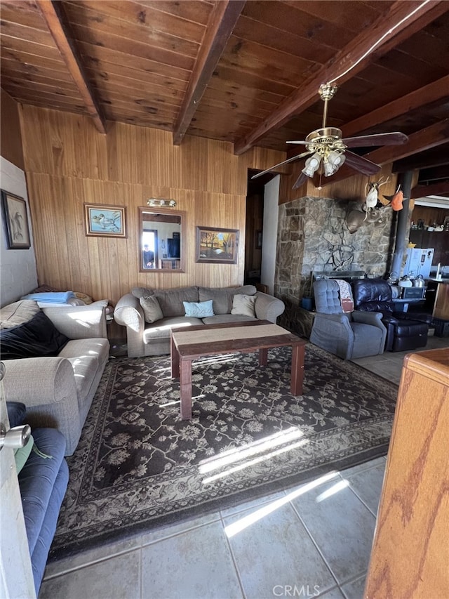 tiled living room with ceiling fan, beam ceiling, wood ceiling, and wooden walls