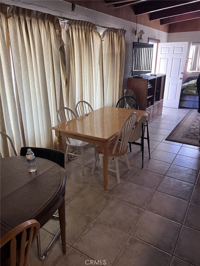 dining space featuring beam ceiling and tile patterned flooring