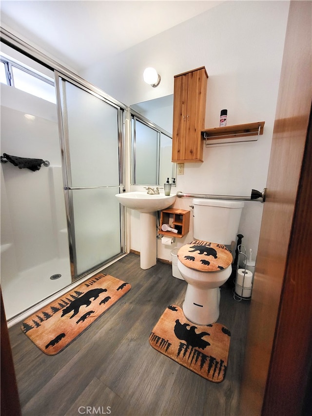 bathroom featuring hardwood / wood-style flooring, toilet, and a shower with shower door