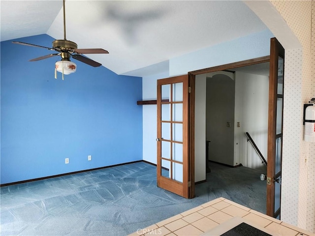 carpeted spare room with ceiling fan, french doors, and vaulted ceiling