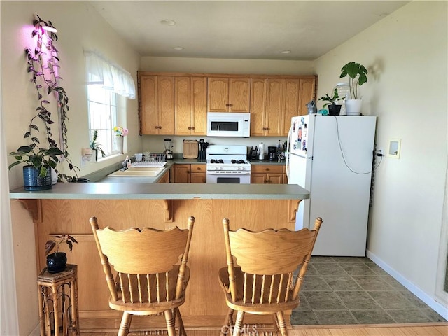 kitchen with kitchen peninsula, sink, dark hardwood / wood-style floors, and white appliances