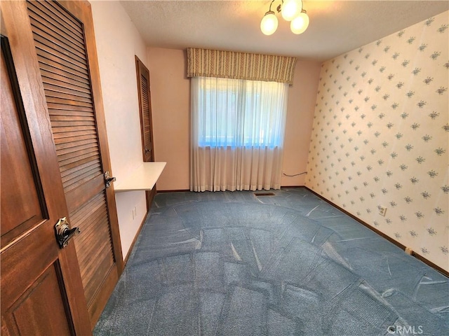 unfurnished bedroom with dark colored carpet, a textured ceiling, and a closet