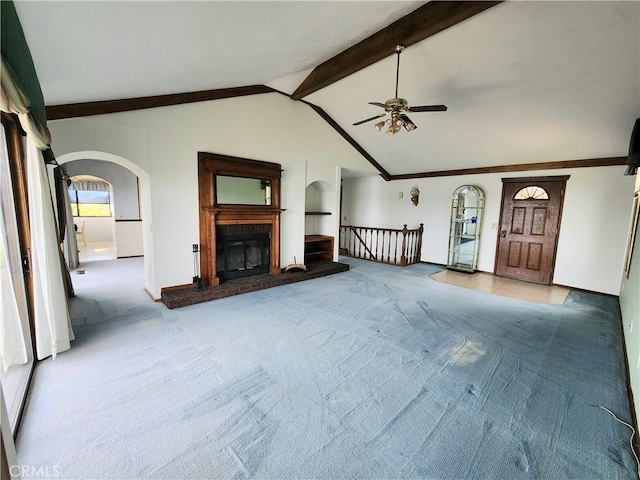 unfurnished living room featuring carpet flooring, vaulted ceiling with beams, and ceiling fan