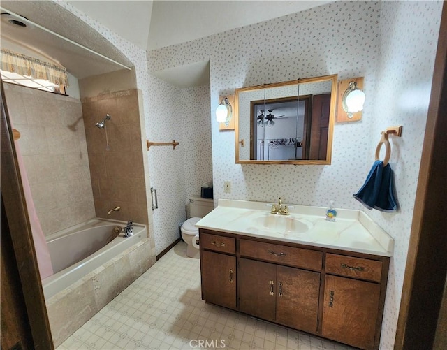 full bathroom featuring vanity, tiled shower / bath combo, and toilet