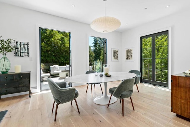 dining room featuring french doors, a healthy amount of sunlight, and light hardwood / wood-style flooring