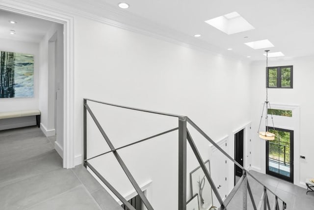 stairway with a high ceiling, ornamental molding, and a skylight