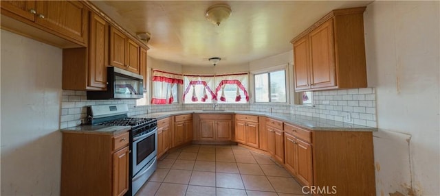 kitchen featuring sink, backsplash, light tile patterned floors, and stainless steel appliances