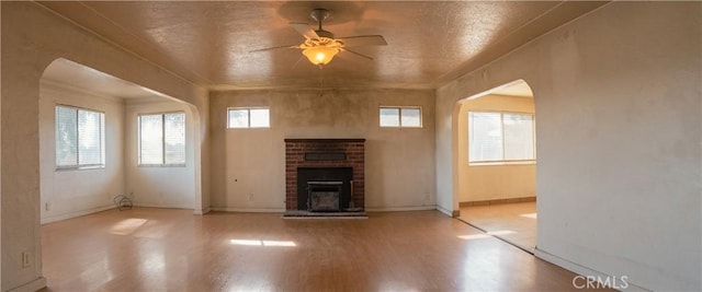 unfurnished living room with light hardwood / wood-style flooring, ceiling fan, a fireplace, and plenty of natural light