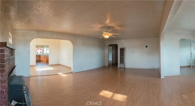 unfurnished living room featuring ceiling fan, light hardwood / wood-style flooring, and a brick fireplace