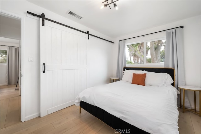 bedroom with light hardwood / wood-style floors and a barn door